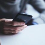 Pessoa segurando um smartphone ao lado de um cartão de crédito, em contexto de serviços financeiros digitais.