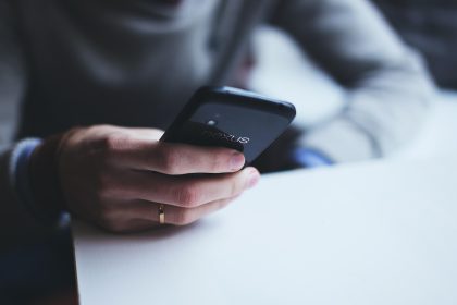 Pessoa segurando um smartphone ao lado de um cartão de crédito, em contexto de serviços financeiros digitais.